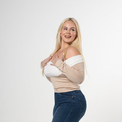 Woman wearing a beige top and blue jeans on a white background