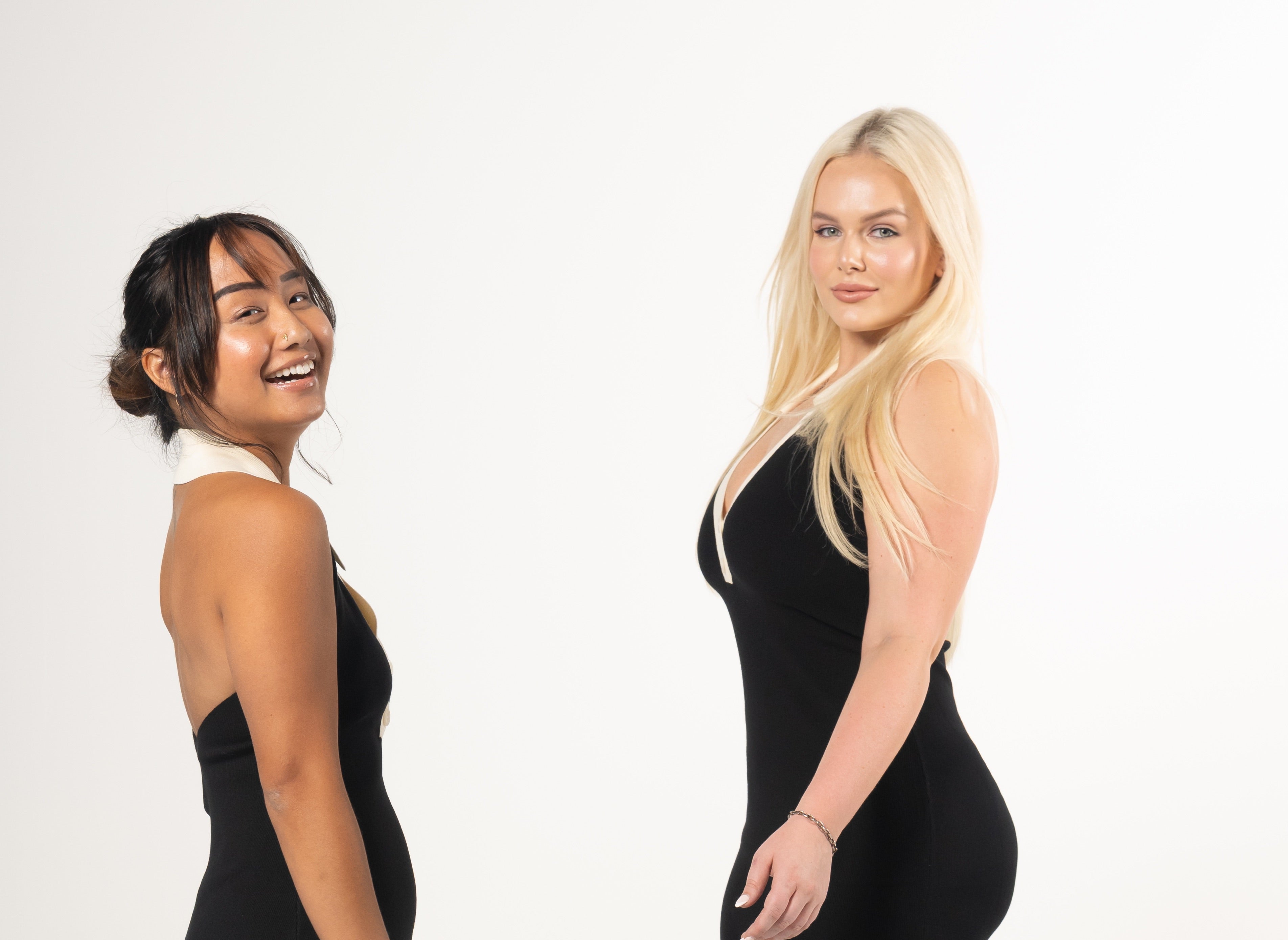 Two women wearing black dresses on a white background